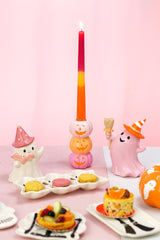 Bougeoir à trois citrouilles souriantes sur une table de goûter d'Halloween avec fantômes pastel