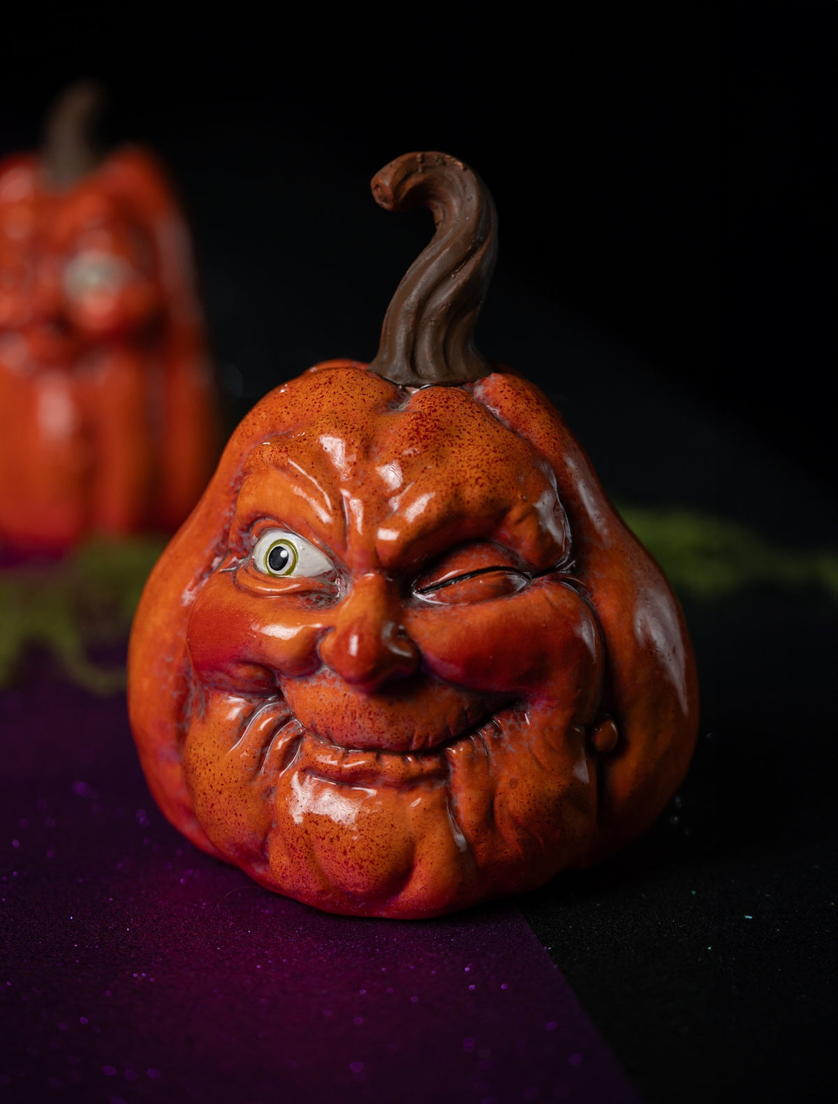 Citrouille Halloween orange à clin d'œil, modèle moyen, en scène sur fond sombre pour une table d'Halloween