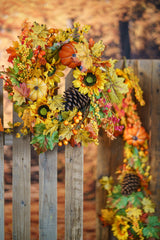 Couronne d'automne à tournesols et citrouilles avec guirlande de feuilles sur une clôture en bois