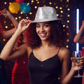 The image shows a silver sequin Borsalino-style hat, commonly used as a party accessory.
