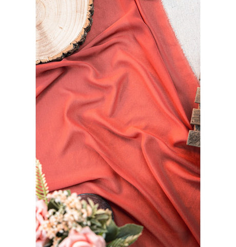 The image shows a roll of decorative fabric or paper in a terracotta color, likely intended for use as a table runner or party decoration.