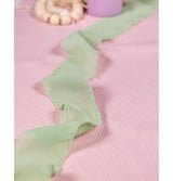 The image shows a sage green decorative ribbon, likely made of fabric, rolled up with a visible texture.
